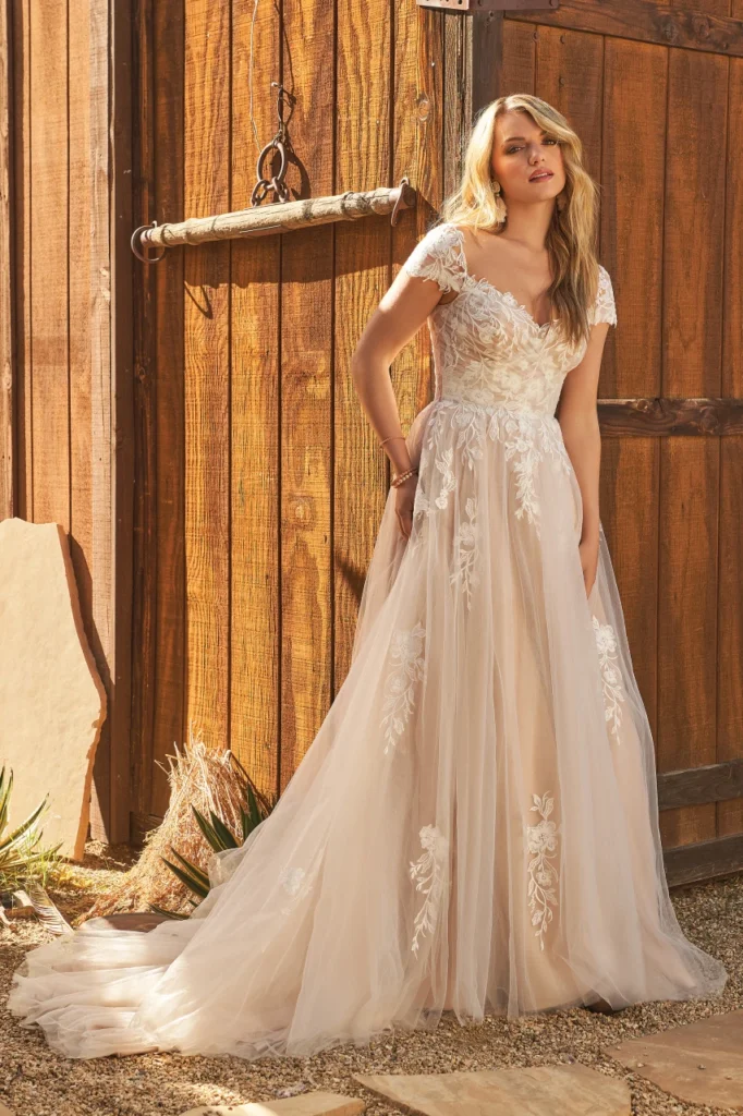 Lillian West style 66259 tulle A-line wedding dress with sweetheart neckline, cap sleeves, and sheer lace bodice, seen in 66259-Lillian West-Pure Bridal.jpg. This romantic gown with a chapel length train is available at Pure Bridal in Edmonton.
