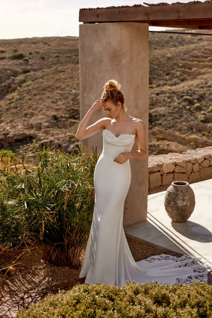 66357-Lillian West-Pure Bridal.Edmonton wedding shop, Edmonton bridal shop, Edmonton wedding dress.Stretch crepe fit and flare gown with strapless sweetheart neckline. Features peek-a-boo sequin lace at sweetheart neckline with cowl draped detail. Buttons down back to start of statement train. Lace trim around hem of skirt starting on sides and extending to cathedral length lace cutout train. Paired with matching sleeves sold separately as 66357SL.