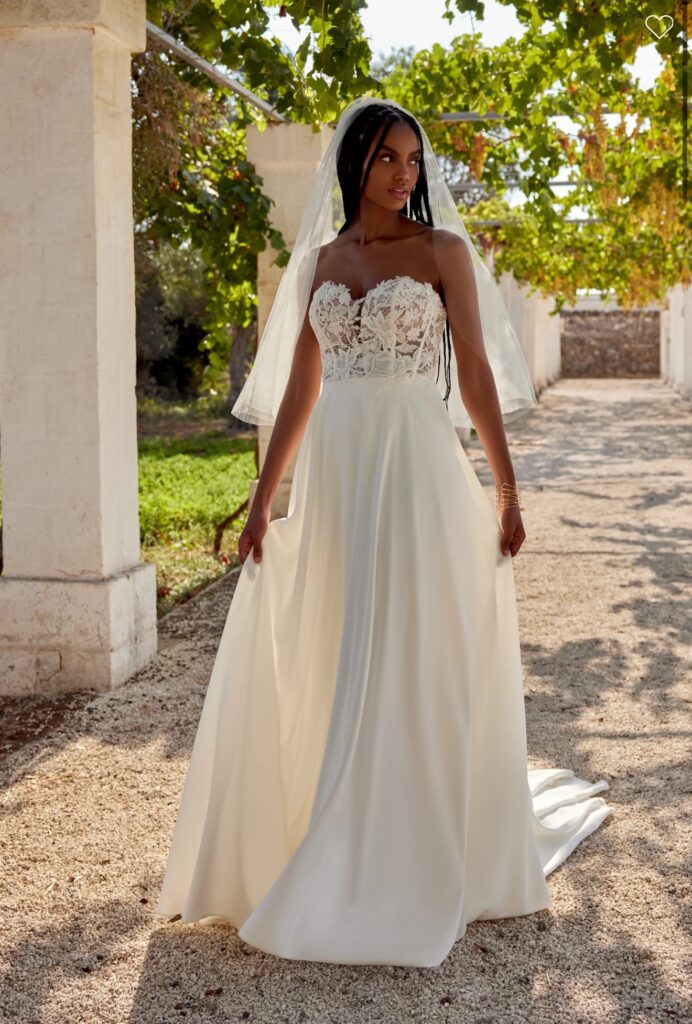 66393-Lillian West-Pure Bridal.Edmonton wedding shop, Edmonton bridal shop, Edmonton wedding dress.Satin A-line dress with plunging strapless sweetheart neckline. Matte lace appliques throughout the sheer bodice lead to a clean skirt with buttons to the end of the chapel length train. Version with bodice lined to side seams available as 66393LND