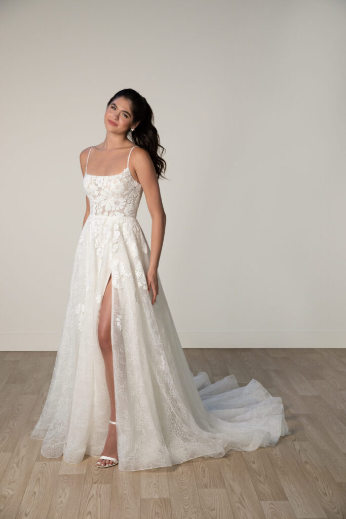 Stella York-8041-Pure Bridal-Style 8041 refreshes bridal fashion with its whimsical yet elegant plus size wedding dress design. This spaghetti strap wedding gown showcases a complementary A-line silhouette thats both classic and modern. From dainty spaghetti straps, the bodice is framed by a modern square neckline in sheer floral lace. From the waist, the skirt blossoms into a textured tulle vision washed with scattered lace appliqus and a striking leg slit that adds a playful element to this contemporary plus size wedding dress-Edmonton Bridal Shop