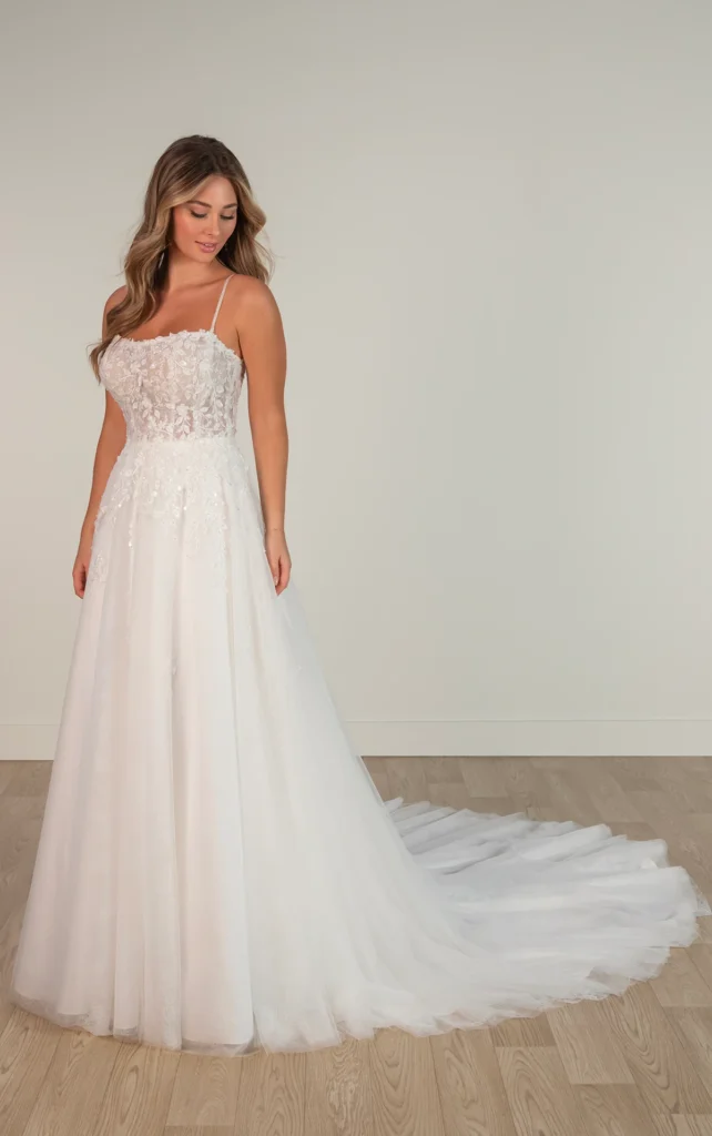 8105-Stella York-Pure Bridal-Edmonton Bridal Shop-Ethereal Leafy Lace A-Line Wedding Dress with Spaghetti Straps  A modern fairytale comes to life with Style SY8105, designed for the romantic at heart. This ethereal lace and tulle wedding dress features a soft, A-line silhouette adorned with delicate, nature-inspired lace for a dreamy, whimsical effect. Beaded spaghetti straps frame a flattering square neckline, leading to a sheer bodice embellished with intricate 3D lace. From the waist, layers of airy tulle cascade into a flowing A-line skirt, creating an effortless sense of movement and weightless elegance. For the bride seeking a touch of magic, this enchanting gown ensures an unforgettable bridal moment. This gown is also available in plus sizes and with a variety of lining options.