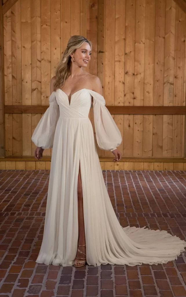 D3636-Essense of Australia-Pure Bridal,Edmonton bridal shop, Edmonton wedding dress. Chiffon A-Line Wedding Dress with Detachable Long Sleeves Get swept away in Style D3636, a romantic A-line wedding dress draped in soft layers of delicate chiffon. The notched plunging neckline accentuates the soft pleating of the romantic wrapped bodice. Detachable off-the-shoulder blouson sleeves add a luxe detail for this versatile wedding look, which can also be worn strapless. The clean and simple aesthetic is made complete with a soft A-line skirt that floats and sways with every movement, with a side slit detail and head-turning train. This wedding gown is also available in plus sizes.