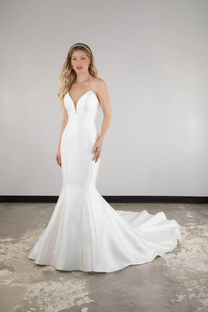 The exquisite Style D3991 is constructed in lustrous Mikado to form a luxe fit-and-flare mermaid wedding gown for the modern bride. A strapless, plunging V-neckline bodice accentuates the natural curves as brilliant contour seam work outlines the figure and paints a gorgeous pedestal for the modern bride. Lining the center of the back from the bodice to the edge of the train, a long row of pearl buttons trails the center back, adding a timeless touch to this contemporary bridal gown. Modern, sexy and refined, this strapless mermaid wedding dress is sure to enchant down the aisle. This gown is also available in plus sizes, Edmonton bridal shop, Edmonton wedding shop, Edmonton wedding dress