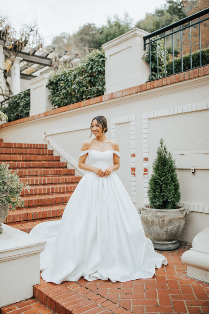 D4110-Essense of Australia-Pure Bridal, SIMPLE MIKADO BALLGOWN WEDDING DRESS WITH OFF-THE-SHOULDER STRAPS Understated luxury shines in this princess-inspired ballgown wedding dress. Style D4110 features sleek off-the-shoulder straps and a flattering scoop neckline as the impeccably tailored bodice hugs the figure with contour seams, fastening into a gown-length row of fabric-covered buttons down the back. At the waist, luscious Mikado cascades into a voluminous ballgown skirt and train, concealing functional side pockets. Luxurious and chic, this Mikado ballgown wedding dress was made for modern royalty. This wedding gown is also available in plus sizes, Edmonton wedding shop, Edmonton wedding dress