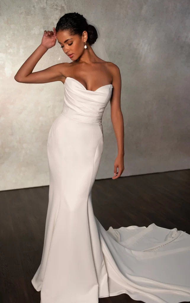 D4193-Essense of Australia-Pure Bridal, Edmonton wedding store, Edmonton bridal shop, Edmonton wedding dress, A clean and chic bridal look comes to life in this stunning strapless satin wedding dress. Style D4193 features a beautifully draped strapless bodice with a flattering sweetheart neckline, the luxurious satin fabric wrapping to the back where a gown-length row of fabric-covered buttons adds a timeless touch to this modern bridal look. Fitted contour seamwork outlines the sleek fit-and-flare silhouette, gracefully flaring into a trumpet skirt just above the knee. This refined strapless wedding gown exudes modern elegance in a simple and figure-flattering look. This wedding dress is also available in plus sizes.