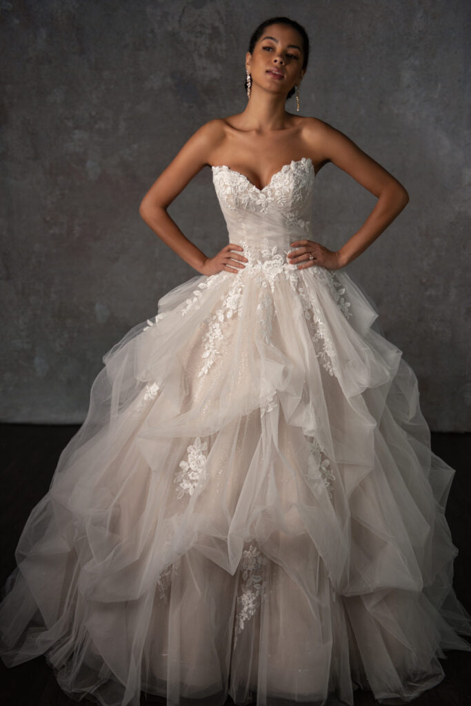 D4345-Essense of Austrailia-Pure Bridal.A contemporary princess ballgown, Style D4345 blends modern runway elements with timeless romance. The lace-adorned sweetheart neckline leads into a luxe fitted bodice, featuring corset-style construction and delicate tulle drapery. A bed of leafy lace appliques wraps the waistline, flowing into a voluminous ballgown skirt made of weightless tiered tulle. With minimalist sophistication, this sparkle tulle wedding dress is designed for the bride who wants to feel like royalty on her special day. This wedding gown is also available in plus sizes.Edmonton wedding shop, Edmonton bridal shop, Edmonton wedding dress.