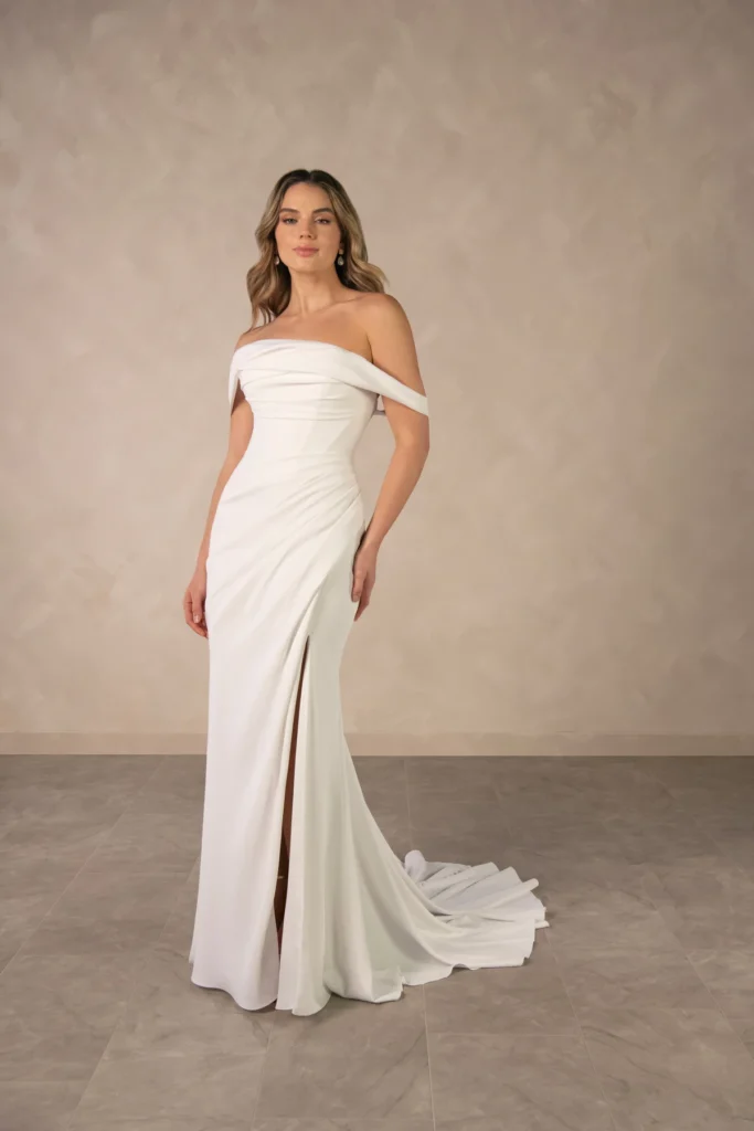 Essense of Australia Style D4563 minimalist off-the-shoulder wedding dress with a skirt slit at Pure Bridal in Edmonton.