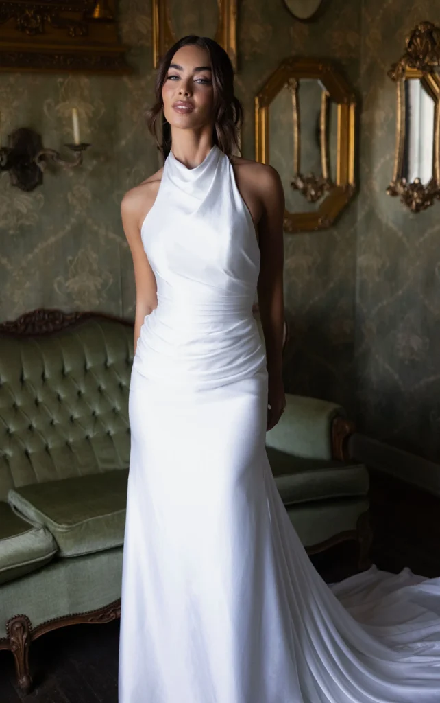 Essense of Australia Style D4614 charmeuse column sheath wedding dress with a softly draped halter neckline, wrapped waist, and detachable bow train at Pure Bridal in Edmonton