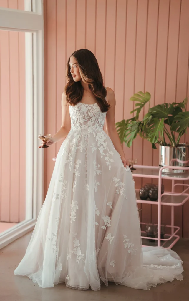 Style SY8213 by Stella York, a romantic floral lace and tulle A-line wedding dress with a sweetheart neckline, sheer tulle bodice with floral appliques, and a subtle blush undertone, available in plus sizes at Pure Bridal boutique in Edmonton.