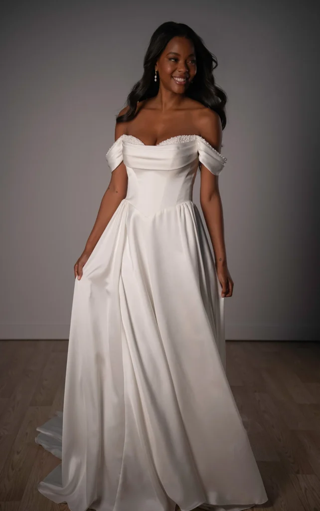 Style SY8236 by Stella York, a sophisticated satin A-line wedding dress with an off-the-shoulder draped band, a peekaboo pearl sweetheart neckline, and a structured basque waist, available in plus sizes at Pure Bridal boutique in Edmonton.
