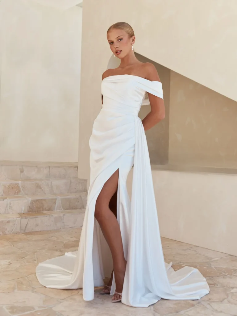 Moon by Serene by Madi Lane satin wedding dress with an off-shoulder neckline, draped bodice, and optional leg split at Pure Bridal in Edmonton